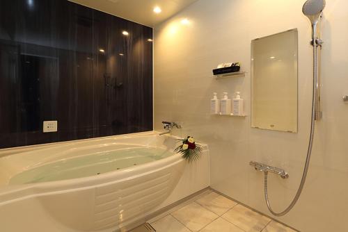 a white bathroom with a tub and a shower at Hotel MOZ in Okayama