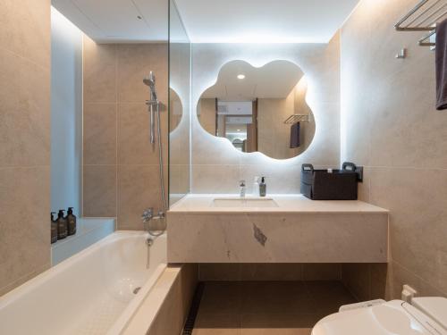 a bathroom with a sink and a tub and a mirror at Urbanstay Residence Dongtan in Hwaseong