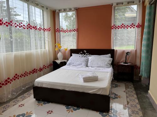 a bedroom with a bed with white sheets and windows at CasaLinda Homestay in Agoho