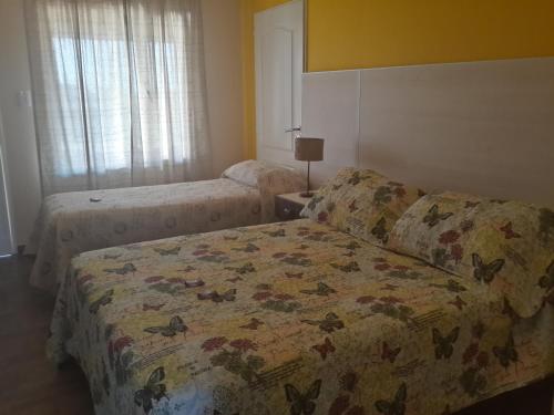 a bedroom with two beds and a bedspread with butterflies on it at Altos de Adonai in Pueblo Quintana