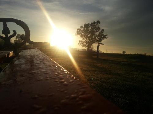 a sun setting over a field with a bench at Altos de Adonai in Pueblo Quintana