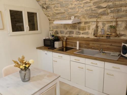 a kitchen with white cabinets and a sink and a counter at Escapade romantique ardéchoise in Villeneuve-de-Berg