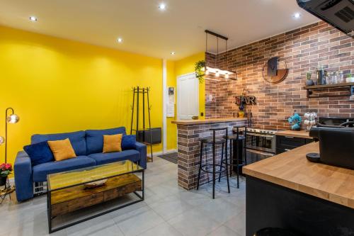 - un salon avec un canapé bleu et un mur jaune dans l'établissement Élégant T2, Centre Paris 20 min, Calme, Cosy, Wifi, à Vincennes