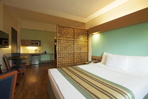a bedroom with a large bed and a kitchen at Microtel by Wyndham South Forbes near Nuvali in Santa Rosa
