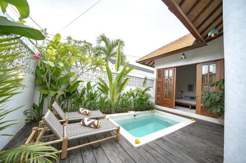 a patio with a swimming pool and chairs and a house at Villa Taman & Villa Serai Kedungu in Tanah Lot