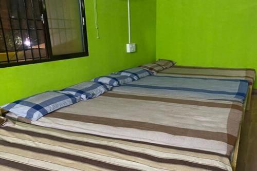a bed in a room with a green wall at Dandeli Eco VanaVasa by StayApart in Dandeli