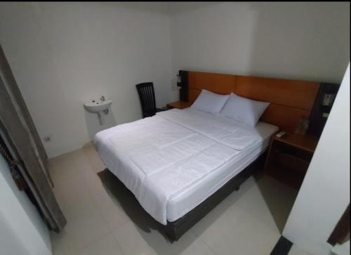 a bedroom with a white bed with a wooden headboard at The Canal Homestay in Probolinggo