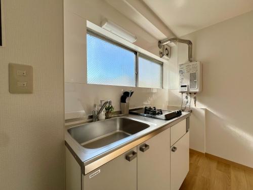 a small kitchen with a sink and a window at nestay apartment tokyo kagurazaka in Tokyo