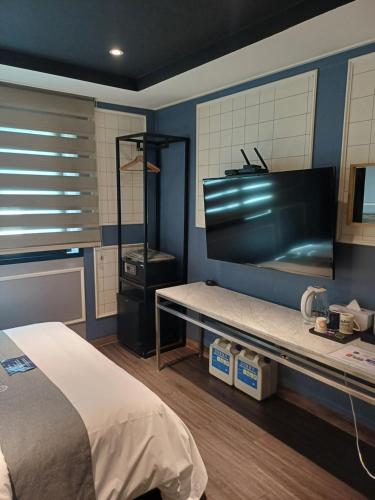 a bedroom with a bed and a flat screen tv at Louis Hotel in Gangneung