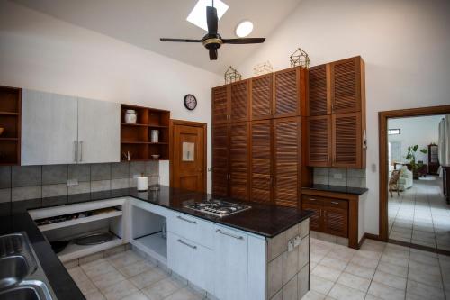 a kitchen with wooden cabinets and a ceiling fan at The Villa - Le Morne - Kite, Golf & Beach in Le Morne