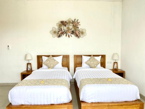two beds in a room with white walls at Kubera Villa Kemenuh by Prasi in Ubud