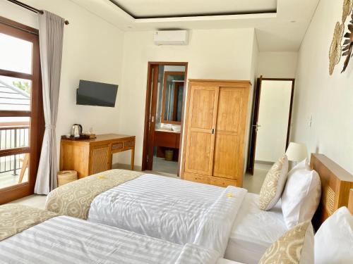 a bedroom with two beds and a desk at Kubera Villa Kemenuh by Prasi in Ubud