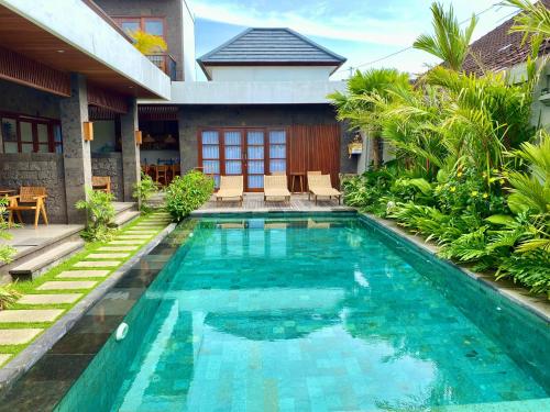 a swimming pool in front of a house at Kubera Villa Kemenuh by Prasi in Ubud