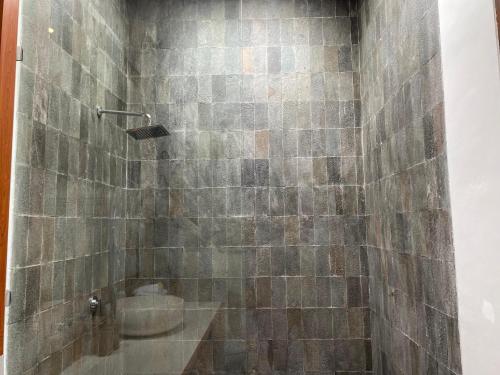 a bathroom with a stone shower with a sink at Kubera Villa Kemenuh by Prasi in Ubud
