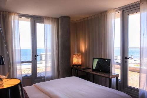 um quarto com uma cama e uma varanda com o oceano em AXSUR Design Hotel em Montevidéu