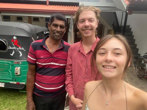 two men and a woman standing in front of a bus at Emerald Coast Hotel Negombo in Daluwekotuwa