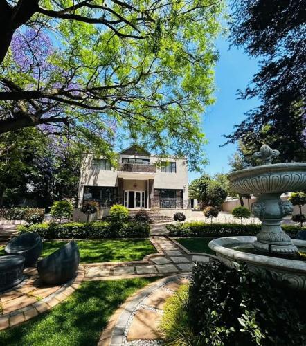 a large white house with a fountain in the yard at 4 Star Hotel in Johannesburg