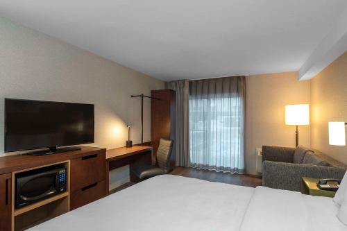 a hotel room with a bed and a flat screen tv at Comfort Inn East in Sudbury