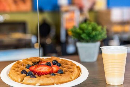 a waffle with fruit on a plate next to a drink at Comfort Inn East in Sudbury
