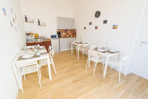 a kitchen and dining room with white tables and chairs at Stabile Hospitality in Trapani