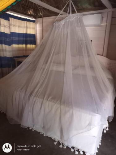 a white bed with a veil hanging from the ceiling at Cabañas y Restaurante La Luna in Boca del cielo