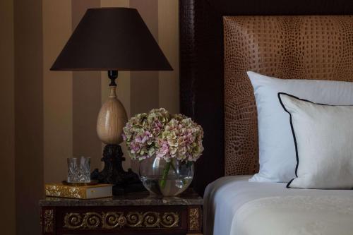 a lamp on a table next to a bed with flowers at Anantara Palazzo Naiadi Rome Hotel - A Leading Hotel of the World in Rome