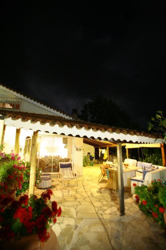 a patio at night with a pavilion with chairs and flowers at Palmina Mare Villa and Studios in Paralia Vrachou