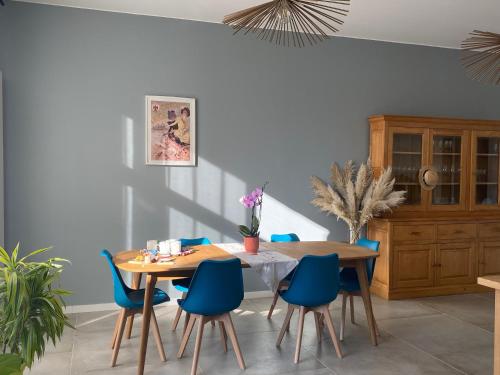 a dining room with a table and blue chairs at Chez Odette chambre saule pleureur in Esnoms-au-Val