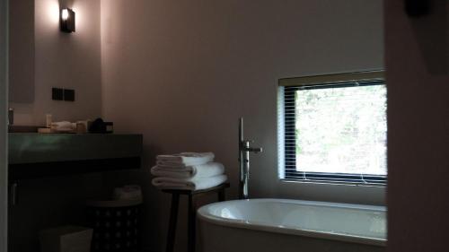 a bathroom with a tub and a window and towels at Resun Hotel宜兴春山在望酒店 in Zhangze