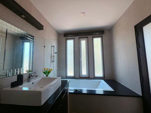 Un baño con una gran bañera blanca y un lavabo. en Baan Chai Hadd, en Pattaya South