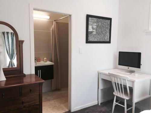 Habitación con escritorio, ordenador y espejo. en Auckland Bungalow Apartment, en Auckland