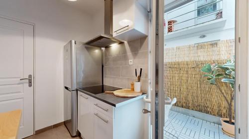 a kitchen with white cabinets and a window at expat renting - Le Volta - Terrasse - Netflix in Toulouse