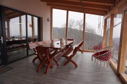 a wooden table and chairs in a room with windows at Cabana Brad Apuseni in Rîmeţi