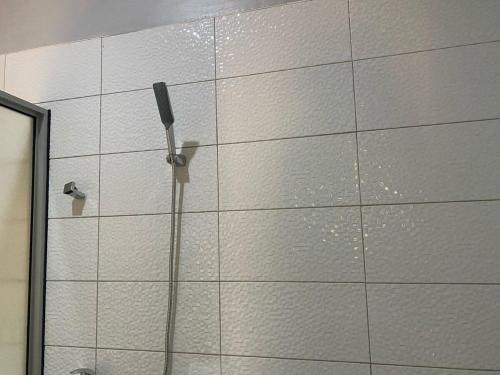 a white tiled wall with a shower in a bathroom at Lovely 4Bedroom Home in Akright - Tara Residence Akright in Buzzi