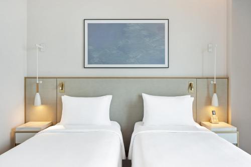 two beds in a hotel room with a picture on the wall at Vida Beach Resort Marassi Al Bahrain in Manama