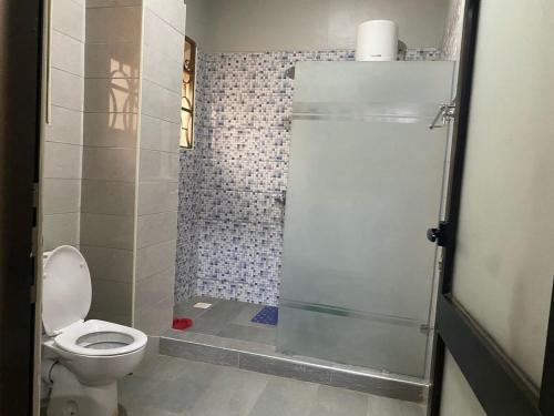 a small bathroom with a toilet and a shower at Lovely 4Bedroom Home in Akright - Tara Residence Akright in Buzzi
