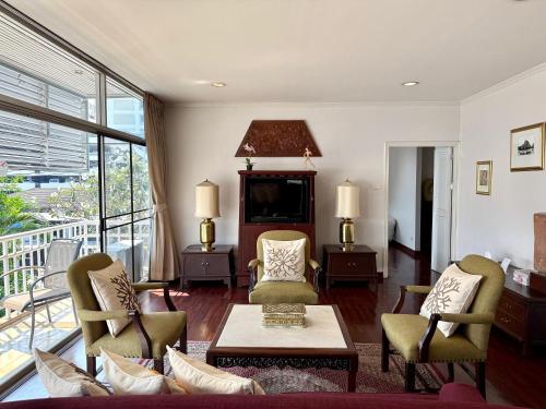 a living room with a couch and chairs and a television at Samsen Suites Spacious 2BR Contemporary Thai Style in Bangkok