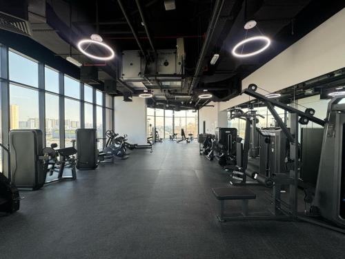 a gym with treadmills and machines in a room with windows at The Community Jumeirah Village in Dubai