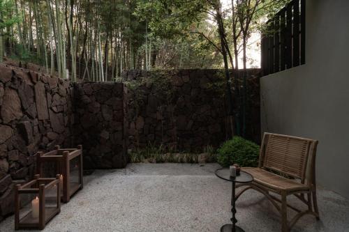 a patio with a chair and a table and a stone wall at Resun Hotel宜兴春山在望酒店 in Zhangze