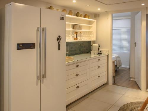 Una cocina con gabinetes blancos y un refrigerador. en Seeplaas Beach House, en Mossel Bay
