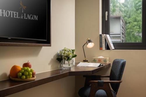 a desk with a television and a bowl of fruit on it at HOTEL de LAGOM in Hanoi
