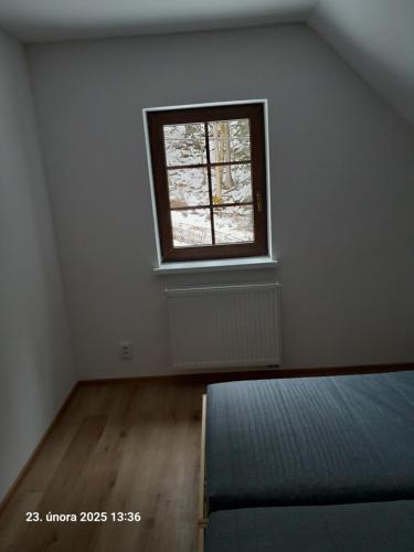 an empty room with a bed and a window at Chata AmBach in Liberk