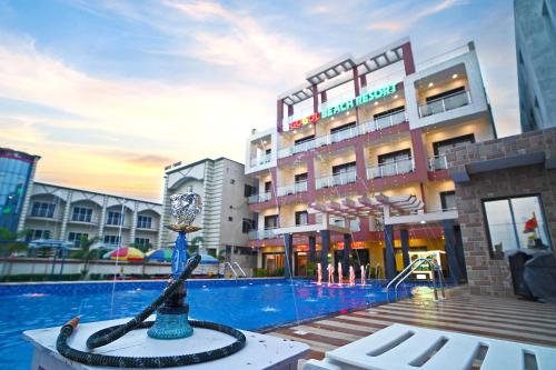 a hotel with a swimming pool with a clock in front of it at Gogol Beach Resort !! Beach 1 Minute !! in Mandarmoni