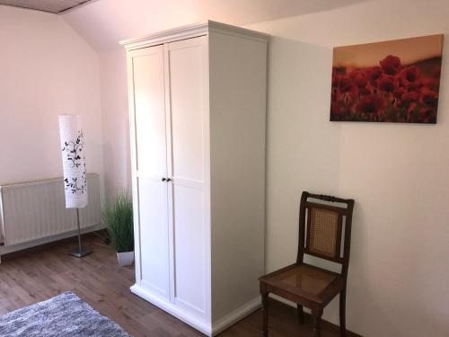 a room with a white cabinet and a chair at Ferienhaus Am Fulda Ufer in Rotenburg an der Fulda