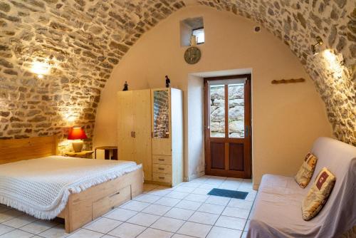 a bedroom with a bed and a stone wall at Gîte La Voûte Céleste 2/3 pers aux Bondons in Les Bondons