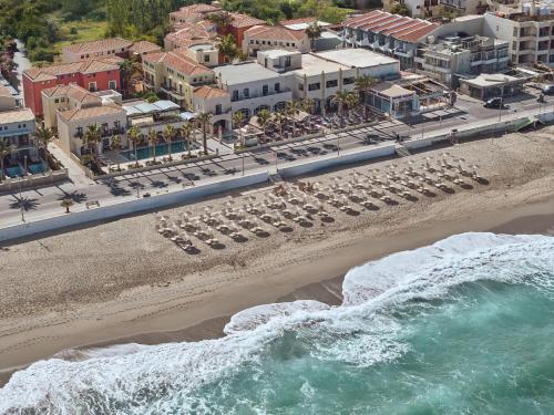 an aerial view of a beach with chairs and buildings at Grecotel Plaza Beach House in Rethymno Town
