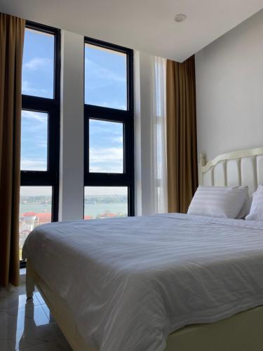 a bedroom with a white bed and two windows at The Vincent Apartment in Phnom Penh