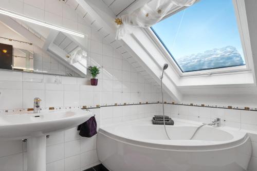baño con lavabo, bañera y ventana en Dachgeschosswohnung in Hofolding, en Brunnthal