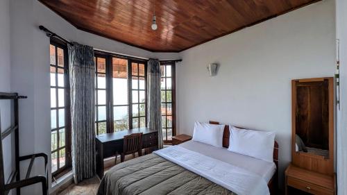 a bedroom with a bed and a desk and windows at The Mist Holiday Bungalow in Haputale
