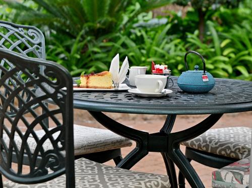 Una mesa negra con un plato de pastel y café encima. en Black Eagle Hotel & Spa, en Roodepoort